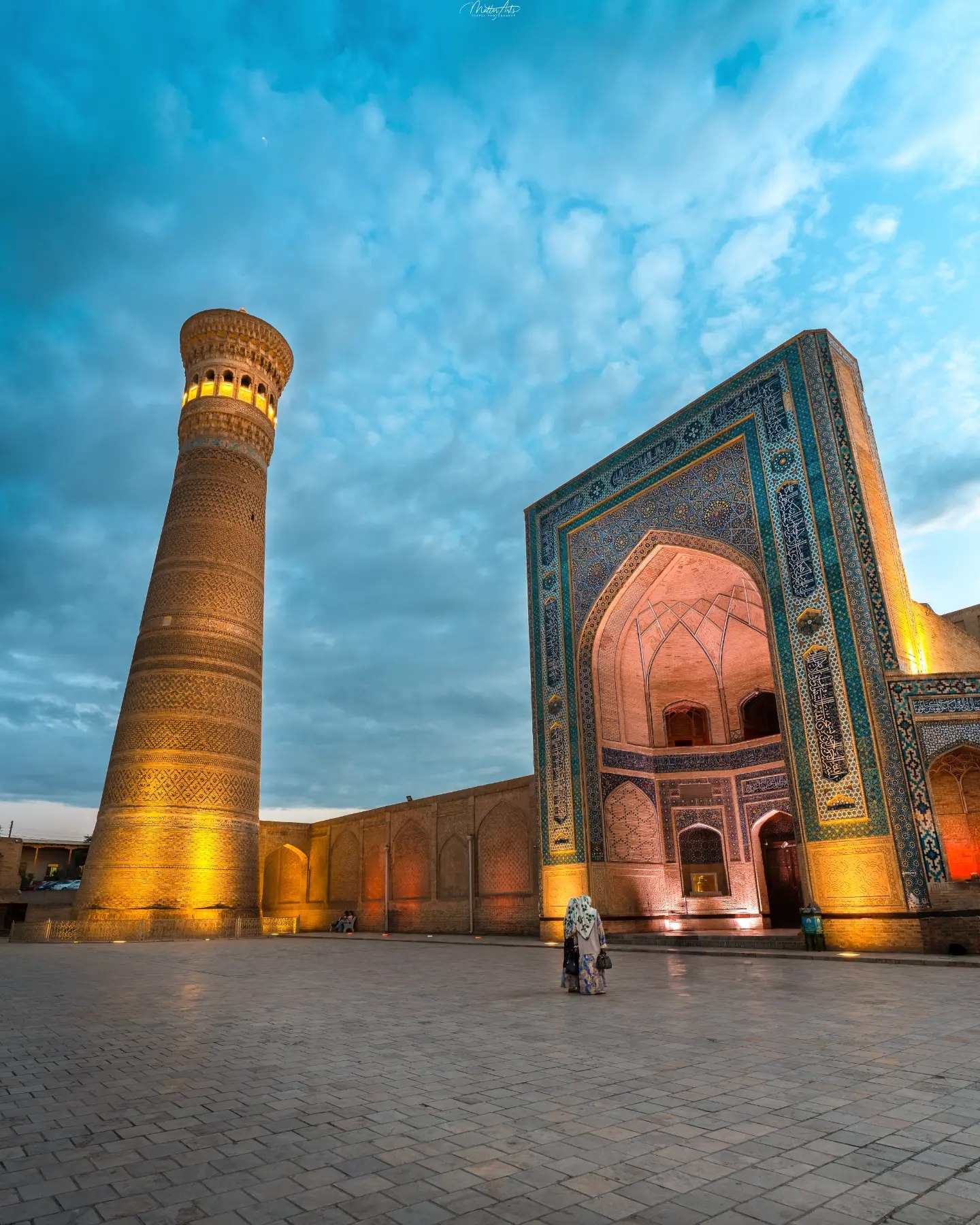 People walking through a courtyard toward the Kalyan Minaret