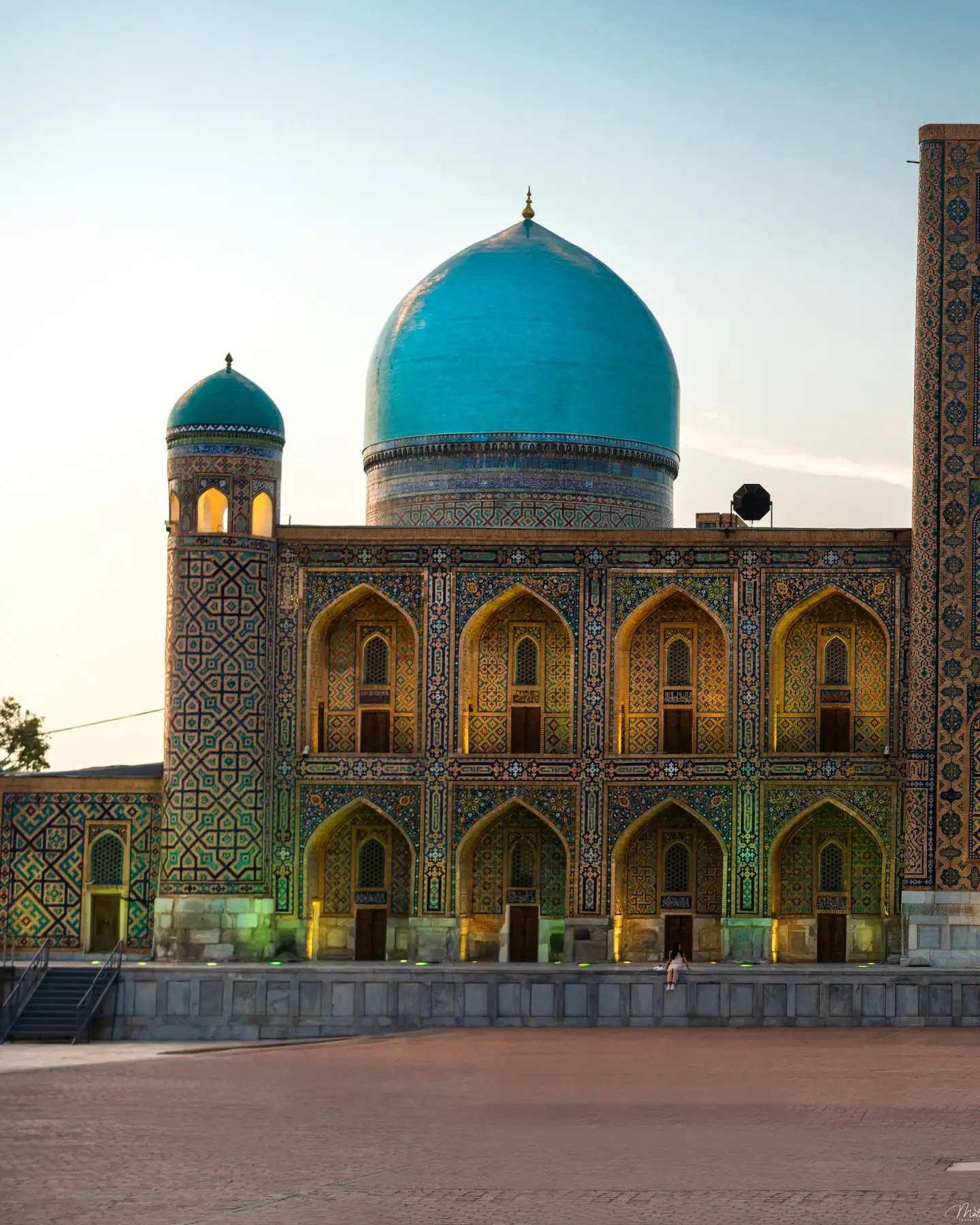 A large tiled mausoleum with a blue dome, photographed after rain