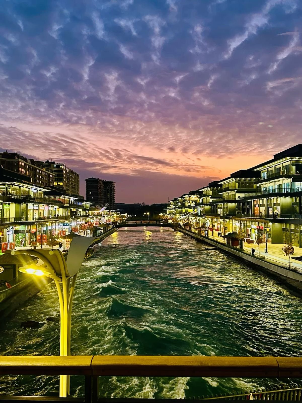 A canal lined with restaurants under a purple and orange sunset sky